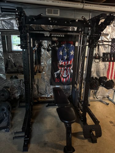Reviewer's black Major Fitness B52 All-In-One Home Gym set up in a basement with a weight bench.