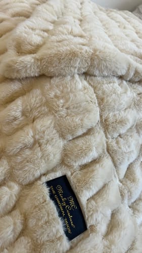 Close-up of the reviewer's plush Hugs Honey Butter Blanket, showing its soft texture and the black brand tag.