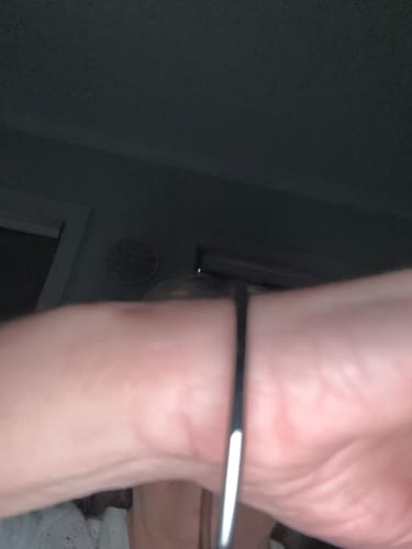 Close-up: A reviewer's wrist wearing the charm bracelet in a dimly lit room, with the charm not visible.