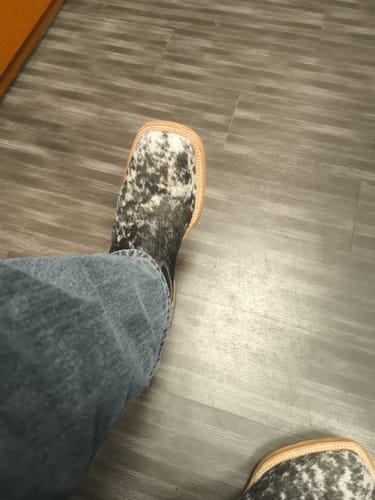 Customer's view looking down at their new square-toed cowhide boots with a black and white pattern.
