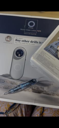Customer's nail drill and its clear handpiece displayed in front of the product packaging.