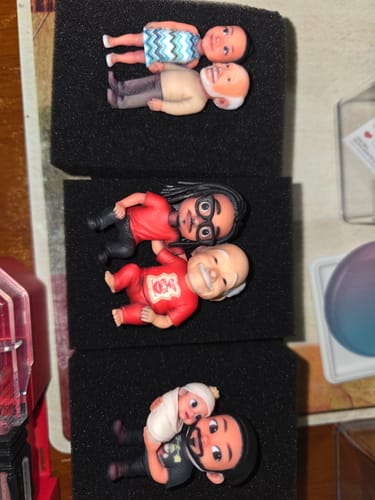 Customer's three cute custom figurines, showing a dad with a girl and two sets with boys, in packaging.