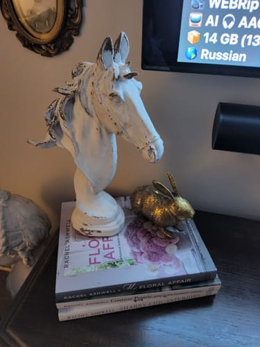 Customer's Apollon horse head bust in distressed white, styled on a stack of books next to a small brass rabbit.
