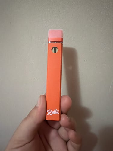Reviewer holding the orange ROLLZ THCA Vape in their hand.