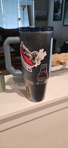 Customer's dark Thicc Buddy 40oz tumbler with a handle, personalized with stickers on a counter.