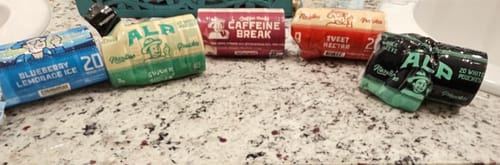 Reviewer's assortment of Drifters nicotine pouches, including Blueberry Lemonade Ice, on a bathroom counter.
