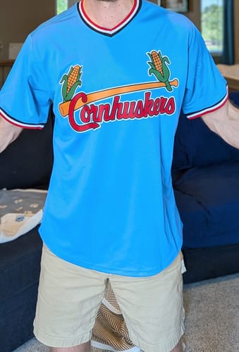 Reviewer wearing a light blue custom baseball jersey with a 'Cornhuskers' graphic and red-white trim.