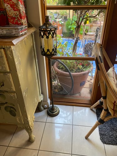 Customer's tall Marc French Provincial Floor Candle Lantern standing indoors on a tiled floor next to a window.