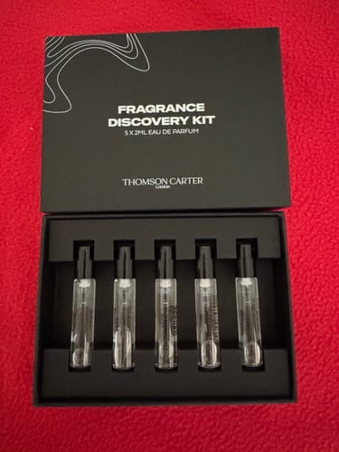 Reviewer's open black Fragrance Discovery Kit box, showing five glass sample vials arranged inside.