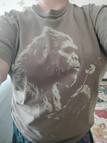 Customer wearing the brown Blowing Wishes T-Shirt, which has a large graphic of an ape blowing on a dandelion.