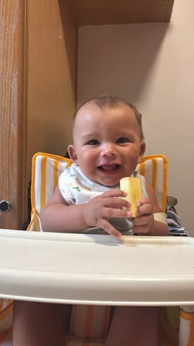 Customer's happy baby sitting in the striped Brighton baby chair with the attached white tray.