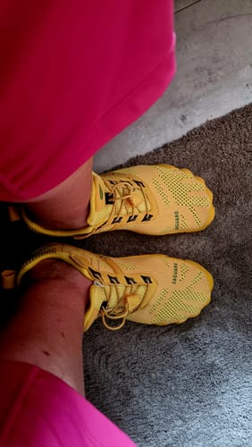 Draufsicht auf die Füße eines Rezensenten in leuchtend gelben Free I Barfußschuhen.