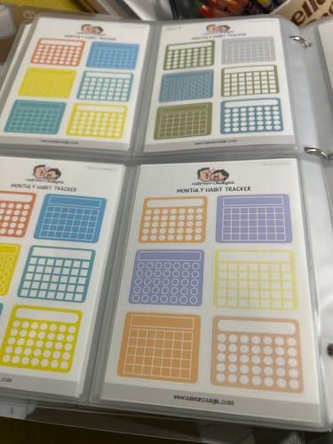 Customer's collection of various Monthly Habit Tracker sticker sheets organized in a binder.