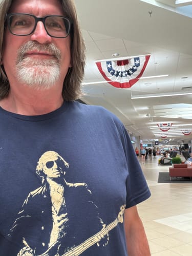 Customer wearing the navy Washington Bass Face T-Shirt in an airport terminal.