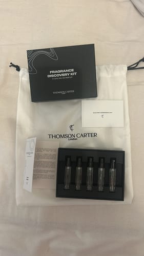 Customer's Fragrance Discovery Kit displayed with its black box, five sample vials, and white branded pouch.
