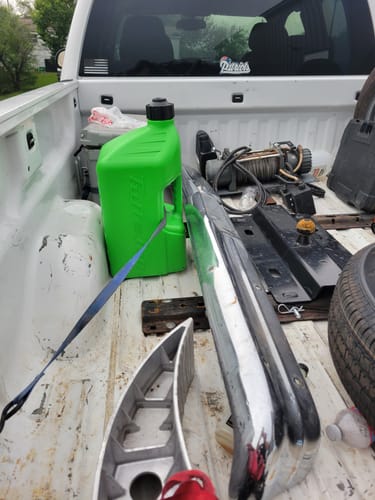 Customer's green fuel can sitting upright in the bed of a white pickup truck among other items.
