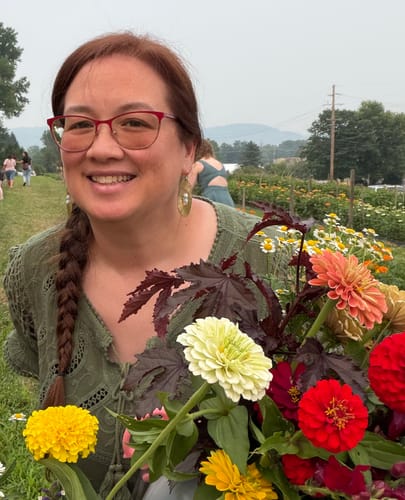 Reviewer smiling in a flower field, wearing a Handmade Illumination Earring.