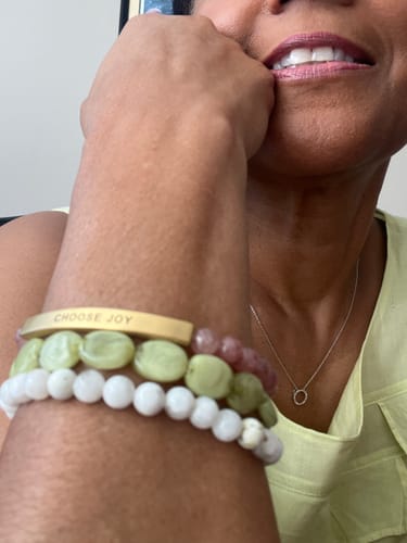 Close-up of a reviewer wearing the CHOOSE JOY bracelet on their wrist, stacked with other beaded bracelets.