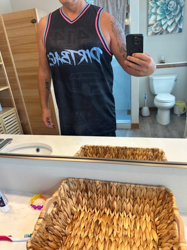 Reviewer wearing their custom black basketball jersey with pink and blue trim.