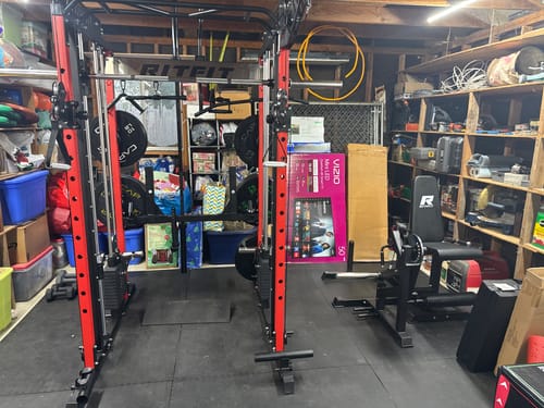 Customer's red and black RitFit M1 Pro with Lat Pulldown and Leg Holder attachments set up in a cluttered home garage.