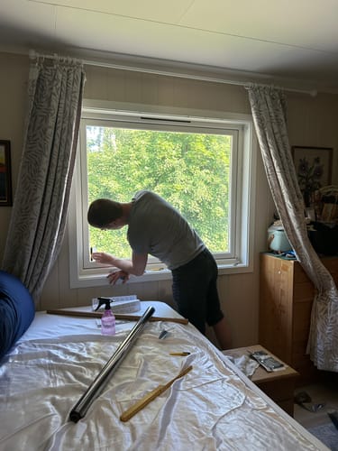 Kunde som monterer Static Reflektiv vindusfolie på et soveromsvindu, med verktøy foran.