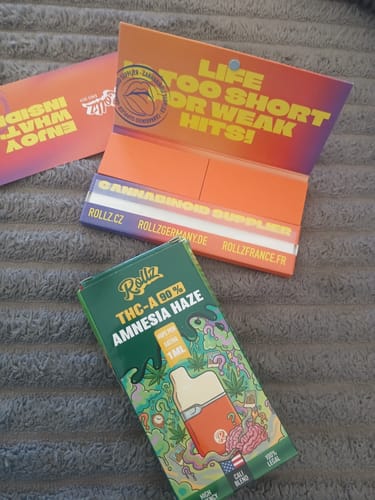 Customer's colorful box for the 1ML THCA VAPE in 'Amnesia Haze' flavor, shown with complimentary rolling papers.
