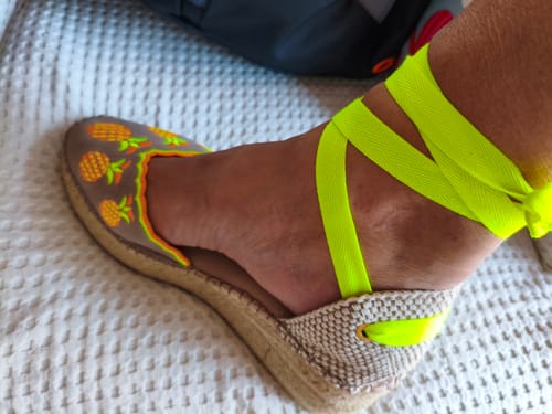 Cliente mostrando una alpargata Carlota Amarillo en el pie, con la brillante cinta amarilla atada al tobillo.