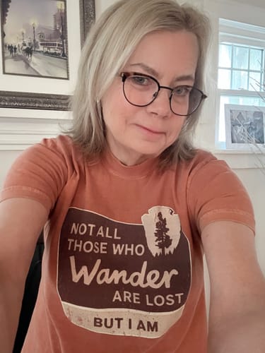 A reviewer takes a selfie wearing the burnt-orange Not All Who Wander T-Shirt.