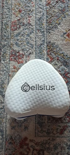 Un client montre le coussin orthopédique blanc et texturé Cellsius posé sur un tapis.