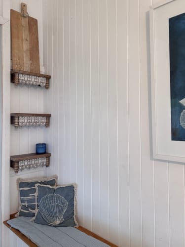 Customer's three Audrey French Provincial Wall Shelves mounted vertically in a corner niche above a bench.