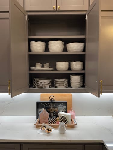 Customer's Pearl White Organic Grand Bowls and matching dishes stored neatly inside an open kitchen cabinet.
