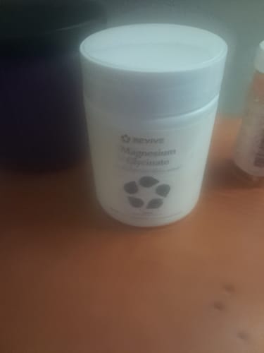 Customer's bottle of Revive Magnesium Glycinate supplement sitting on a wooden surface.