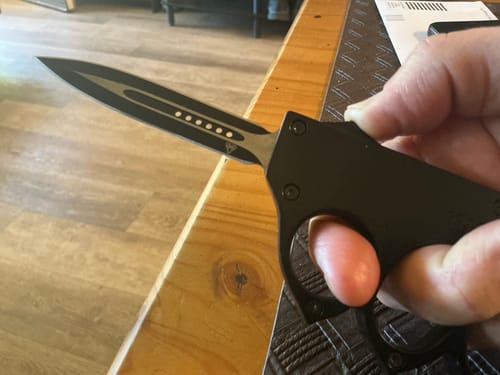 Close-up of a customer holding a black knife with a knuckle duster style handle.