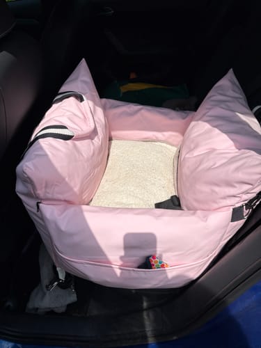 Customer's pink Dog Dock V2 installed securely in the back seat of a car, showing its cushioned interior.