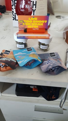 Customer's First Taste Bundle, showing three colorful pouches and two small jars of THCA flowers on a white shelf.