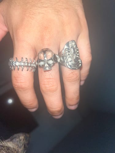 Customer's hand wearing the detailed RISING SCORPIO RING on the ring finger, next to two other silver rings.