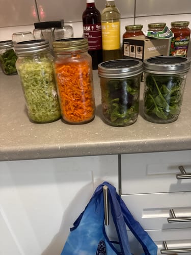 Customer shows four glass jars of fresh, chopped vegetables sealed on a kitchen counter after using the Mason Genie Vacuum Sealer Kit.