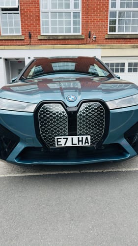 Reviewer's light blue BMW iX showing the clean license plate look achieved with the OEM Plinth Delete Kit.