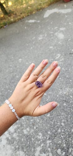 Cliente montrant la bague dorée en améthyste brute portée à son doigt.