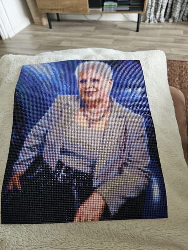 Ein Kunde zeigt sein fertiges Diamond Painting eines eigenen Fotos, das ein Porträt einer Frau ist.