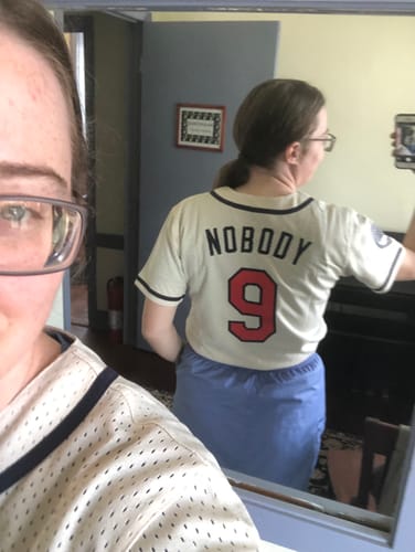 image 2 out of 3: Reviewer showing the back of their custom jersey in a mirror, with 'NOBODY' and the number 9 in red and navy.