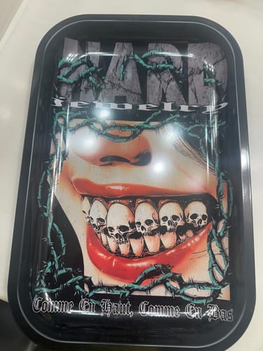 Customer's black jewelry tray with a graphic design of a mouth with skull-shaped teeth surrounded by thorny vines.