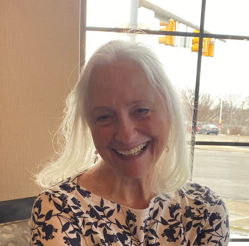 Smiling customer with white hair by a window, customer photo