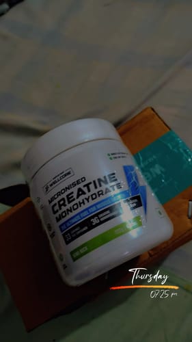 Customer's photo of the white Wellcore Micronised Creatine Monohydrate tub, Kiwi Kick flavor, resting on a box.
