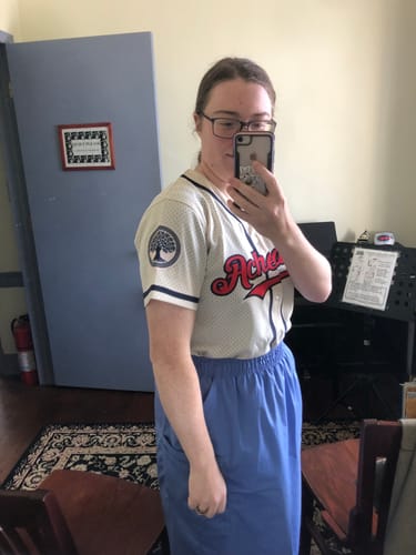 image 3 out of 3: Side view of a reviewer wearing the custom cream baseball jersey, highlighting a custom circular tree patch on the sleeve.
