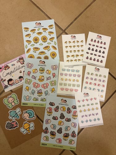 Reviewer's complete Sunflower Critters Sticker Set, with all the cute sticker sheets spread out on a tiled floor.
