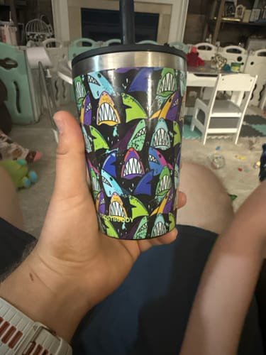 Customer holding their Junior Buddy Fin Frenzy cup, which is covered in a colorful shark pattern.