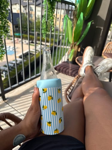 Customer's Universal Buddy Main Squeeze cooler holding a glass bottle while relaxing on a balcony.