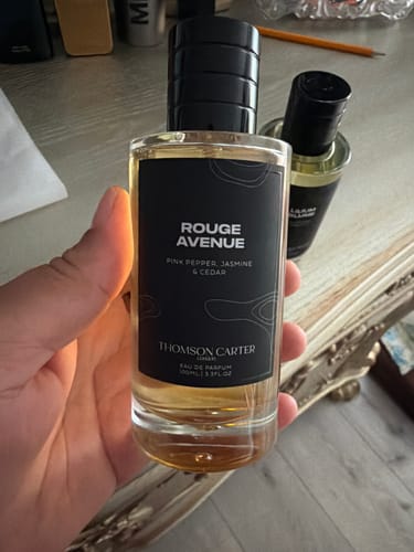 Customer holding the clear Rouge Avenue Eau de Parfum bottle with a black label.