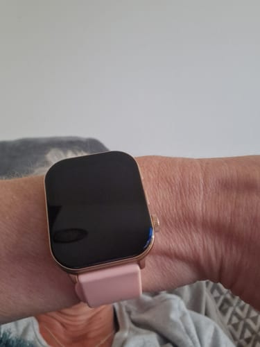 Reviewer showing their smartwatch with a rose gold case and a pink band on their wrist.